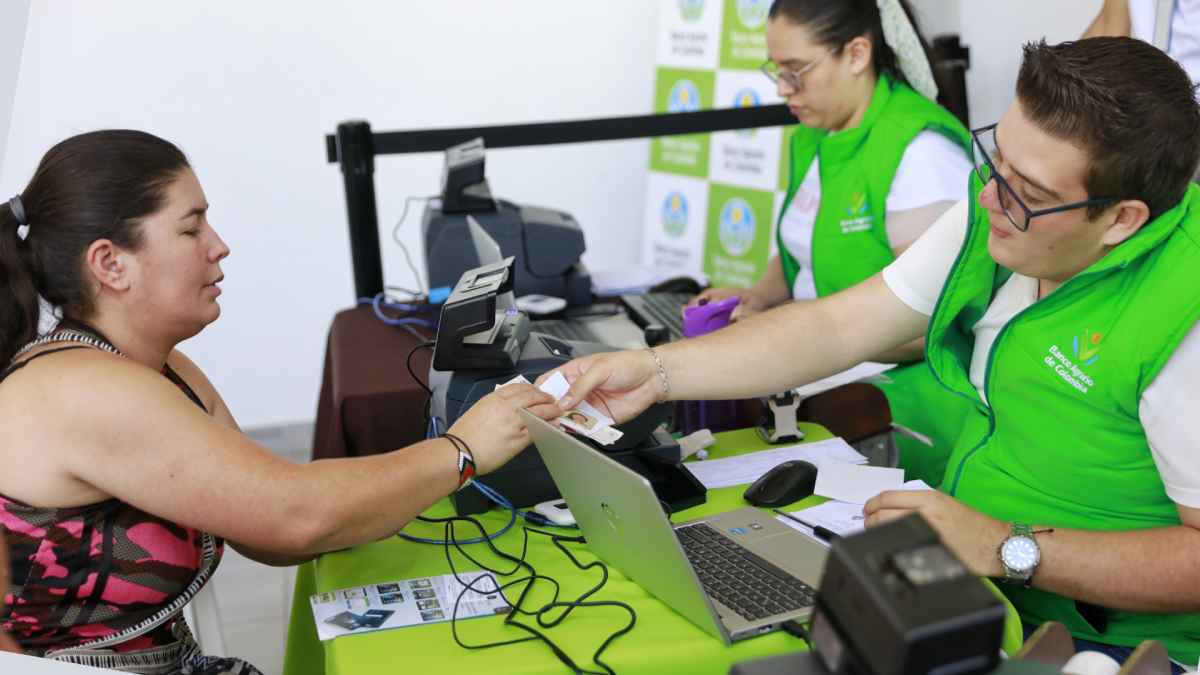 Funcionario del Banco Agrario de Colombia entregando el dinero a beneficiaria del subsidio Tránsito a Renta Ciudadana