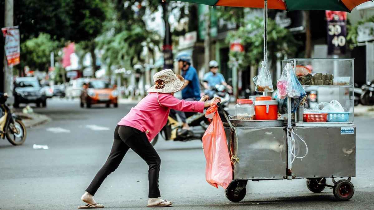 Creo: La Nueva Alternativa de Crédito del Gobierno para Desafiar al 'Gota a Gota - Vendedora ambulante empujando carrito en la calle.