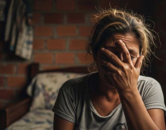 Mujer en pobreza tapándose la cara con una mano.