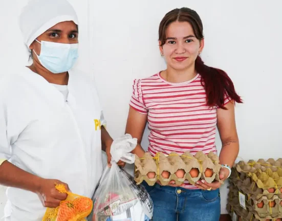 Foto: PAE Colombia UApA - Mujer recibiendo canastas alimentarias para preparar en casa durante el receso de fin de año 2025.