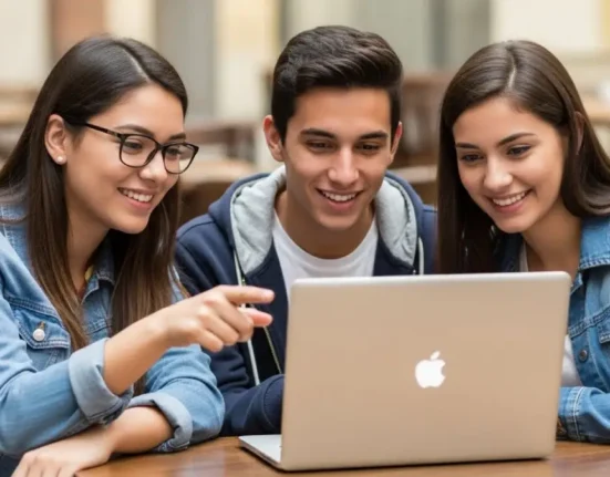 Tres jóvenes mirando un macbook apple - becas para estudiar en 2026