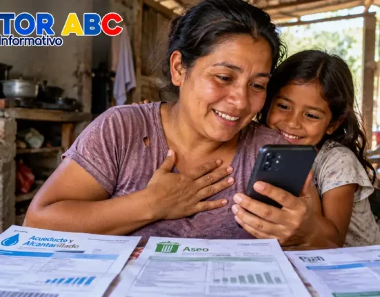 Madre e hija revisan un celular junto a recibos de agua y aseo en una vivienda humilde, imagen sobre alivios en servicios públicos.