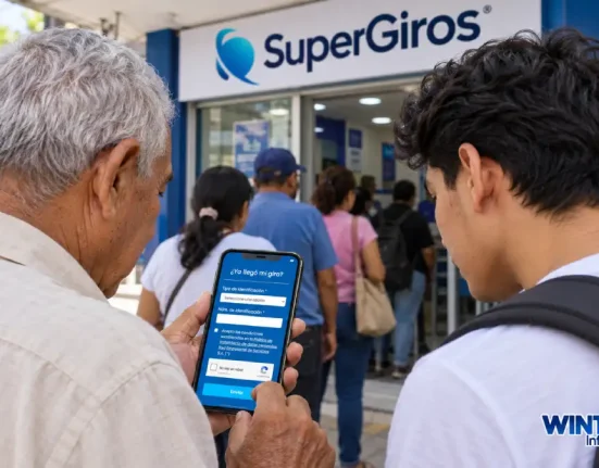 Adulto mayor y joven miran un celular frente a un punto de SuperGIROS con personas en fila.