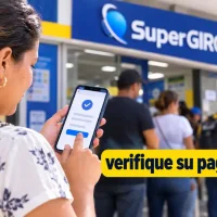 Mujer consulta en su celular el pago de la UNGRD frente a un punto de SuperGIROS.