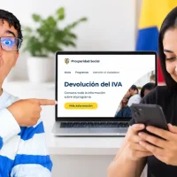 Devolución del IVA: mujer consulta información del programa en su celular junto a un computador con la página oficial